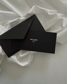 two black envelopes sitting on top of white sheets