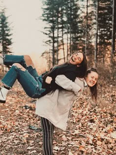 two girls are playing in the leaves on an autumn day with their arms around each other