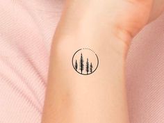 a woman's arm with a small tattoo of trees in the middle of it