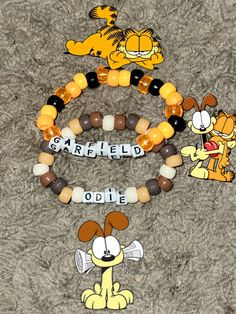 three beaded bracelets with cartoon characters on them, one has a dog and the other has a cat