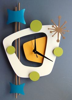 a clock that is on the wall with blue and green decorations around it's face