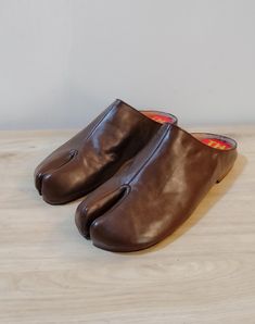 Beautiful handmade leather Japanese Tabi mules  with split toe design,completely hand stitched from top to bottom. The boots are made with soft supple leather and are very comfortable and will mold to your foot with time. Pre order: Please note these mules are made upon order and will take 4-6 weeks to complete and ship. Handmade with top quality materials and stacked leather soles. The shoes will have minor imperfections do to handmade handling and painting. Sizes: 7-11 or 37-41 Please contact Leather Mules With Plain Toe And Stitched Sole, Leather Mules With Stitched Plain Toe, Leather Mules With Stitched Sole And Plain Toe, Leather Slip-on Mules With Single Toe Strap, Leather Mules With Rubber Sole And Single Toe Strap, Brown Leather Slippers With Almond Toe, Leather Square Toe Mules With Rubber Sole, Leather Clogs With Single Toe Strap And Rubber Sole, Leather Mules With Single Toe Strap And Leather Lining