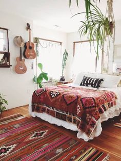 a bedroom with a bed, rugs and guitar hanging on the wall