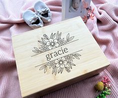 a wooden box with the word grace written on it next to some baby's shoes