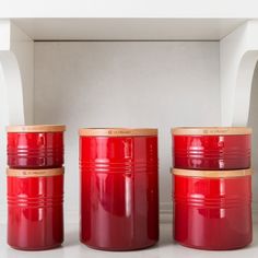 three red canisters sitting next to each other on a white countertop in front of a wall