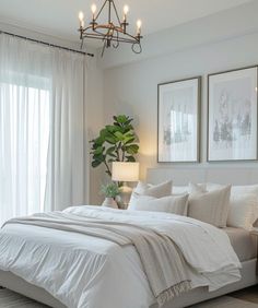 a white bed sitting in a bedroom next to two framed pictures on the wall above it