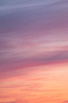 an airplane flying in the sky at sunset