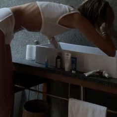 a woman bending over in front of a bathroom sink