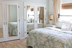 a bedroom with mirrored closet doors in the middle and a bed on the other side