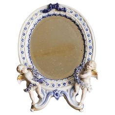 an ornate blue and white mirror with cherubs on the bottom, in front of a white background