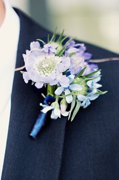 a boutonniere with purple flowers and greenery is worn on a man's lapel