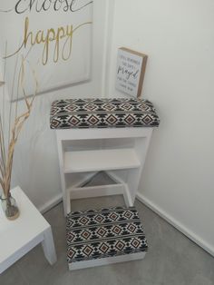 a white step stool with a black and white patterned footstool next to a sign that says choose happy