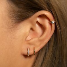 a close up of a person wearing two different rings on their ear and one has a diamond in the middle