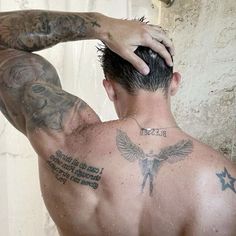 a man with tattoos on his back is looking at himself in the mirror and holding his head