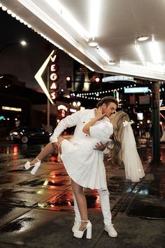 a man and woman dressed in white posing for a photo on the street at night