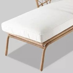 a wicker chaise lounger with white cushions on it's back end