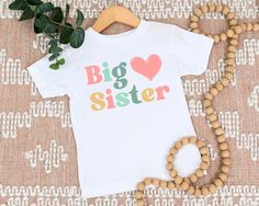 Big Sister t-shirt T-shirt is 100% Australian cotton.  We design & print our products with care & love! We use the best quality vinyls, inks & transfers on all products. * * * * * * * * * * * * * * * * * * * * * * * * * * * * * CARE INSTRUCTIONS: Wash inside out on gentle wash, Do not tumble dry. * * * * * * * * * * * * * * * * * * * * * * * * * * * * * SHIPPING: We want to get your product to you as quickly as possible, your purchase will be shipped through Australia post, Express post is available for selection. * * * * * * * * * * * * * * * * * * * * * * * * * * * * * GUARANTEE: We stand behind our products with a 100% guarantee; if you are unsatisfied with our product, please let us know & we will rectify any issues. We are unable to refund products due to change of mind or those that White Cotton T-shirt As Gift, White Letter Print T-shirt For Gender Reveal, White Graphic Tee For Gender Reveal, Personalized Name Print White Shirt As Gift, White Tops With Name Print For Gift, White Shirt With Name Print For Gift, Crew Neck T-shirt For Gender Reveal With Text Print, White Short Sleeve T-shirt For Gender Reveal, White Short Sleeve Tops For Gender Reveal