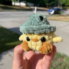 a hand holding a small stuffed animal wearing a hat