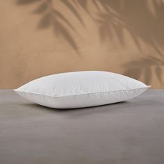 a white pillow sitting on top of a table next to a brown wall and palm tree