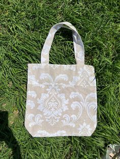 a tote bag sitting on top of a green grass covered field next to a pair of shoes