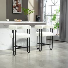 two white bar stools sitting in front of a counter