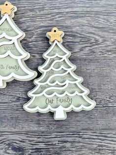 two christmas tree cookie cutters on top of a wooden table next to each other