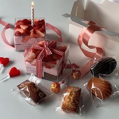 two boxes filled with pastries next to a candle and some heart shaped candies