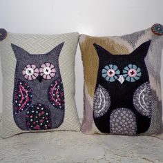 two decorative pillows are sitting on a bed with white linens and lace, one has an owl applique