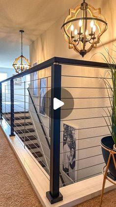 a stair case with pictures on the wall next to potted plants and a chandelier