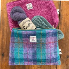 three different colored plaid bags with yarn and knitting needles in them on a wooden surface