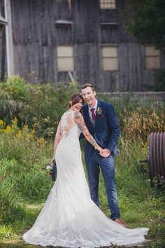 a bride and groom standing in front of an old barn