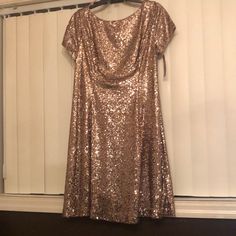 a gold sequin dress hanging on a clothes hanger in front of a window