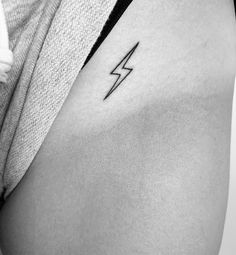 a black and white photo of a woman's stomach with a lightning tattoo on it