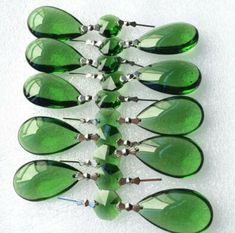 a bunch of green glass drops sitting on top of a white surface