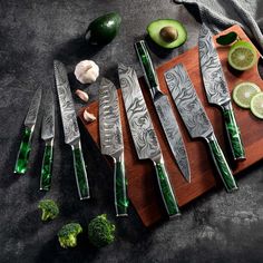 the knives are next to some broccoli and limes on a cutting board