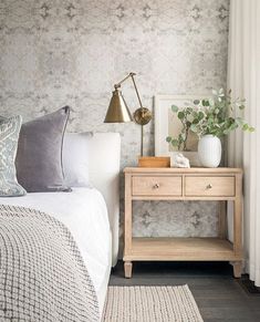 a white bed sitting next to a wooden night stand