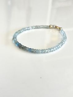 This gorgeous beaded bracelet is made up of beautiful shaded aquamarine faceted rondelles. The stones have beautiful ombre shades of mostly light through deeper blues and greens.  Finished with a 14k Gold Filled clasp and findings. Each end of the bracelet features a crimp cover bead and one bead is wire wrapped and dangles from the end of the bracelet.  Aquamarine is the birthstone for the month of March.  This bracelet is fairly dainty - gemstones measure approximately 3.5mm - 4mm. Bracelet measures 7 inches total. This can be made with or without an extension chain on request. Please leave a note at checkout.  Your bracelet will arrive in a gift box. Blue Faceted Rondelle Bracelets, Blue Rondelle Beaded Bracelets, Everyday Faceted Rondelle Bracelets, Aquamarine Bracelet, Jewelry Dainty, Aquamarine Jewelry, San Clemente, March Birthstone, Stackable Bracelets