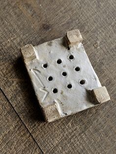 a piece of concrete sitting on top of a wooden floor with holes in the middle