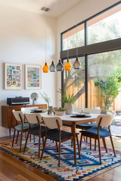 the dining room table is surrounded by modern chairs and rugs that match the hardwood flooring