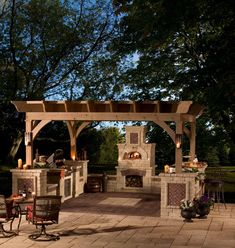 an outdoor kitchen and dining area is lit up at night with candles on the table