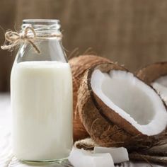 a glass bottle filled with milk next to some cut up coconuts on a table