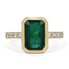 A remarkable emerald and diamond engagement ring. The center stone showcases a striking natural Zambian emerald with superior characteristics such as its deep green color, very good luster, and clarity. Natural internal inclusions are common in all earth-mined gems and are what make each one stand out for themselves. The emerald is securely bezel set with eight (four on each side) brilliant round cut diamonds, four on each side, pave set for the utmost shine and visibility. Crafted in smooth sol Radiant Cut Emerald Ring With Center Stone, Emerald Ring With Center Stone And Emerald Cut, Classic Emerald Ring With Tsavorite Accent Stones, Timeless Emerald Ring With Accent Stones, Emerald Baguette Cut Ring With Bezel Setting, Bezel Set Baguette Cut Emerald Ring, Baguette Cut Emerald Ring With Bezel Setting, Baguette Cut Bezel Set Emerald Ring, Rectangular Emerald Ring With Diamond Accent Stones