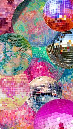 colorful disco balls hanging from the ceiling in front of a wall with many colors and shapes