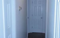 an empty hallway with a white door and black carpeting on the floor in front of it