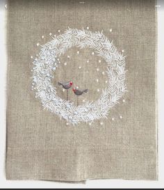 a piece of cloth with a bird on it and a wreath in the middle that is embroidered onto