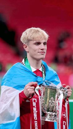 a young man holding up a silver cup in his hands and scarf around his neck