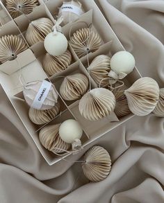 a box filled with white ornaments on top of a beige cloth covered bed sheet,