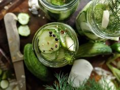 cucumbers and herbs in jars on a cutting board