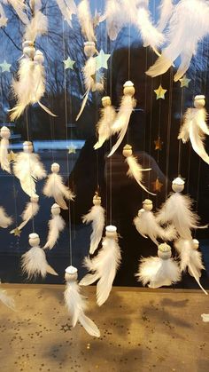 white feathers and stars hanging from strings in a window