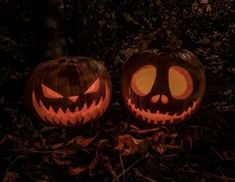 two carved jack o lantern pumpkins sitting on the ground with their faces lit up